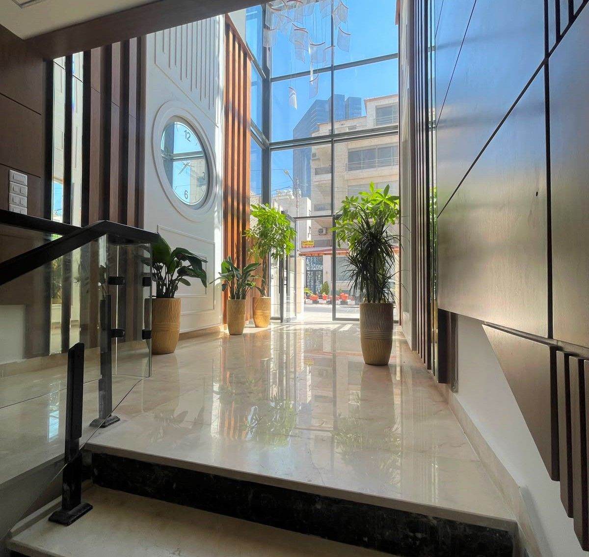 The entrance hall of a completed building — marble floor, full-height glazing onto the street and planting.